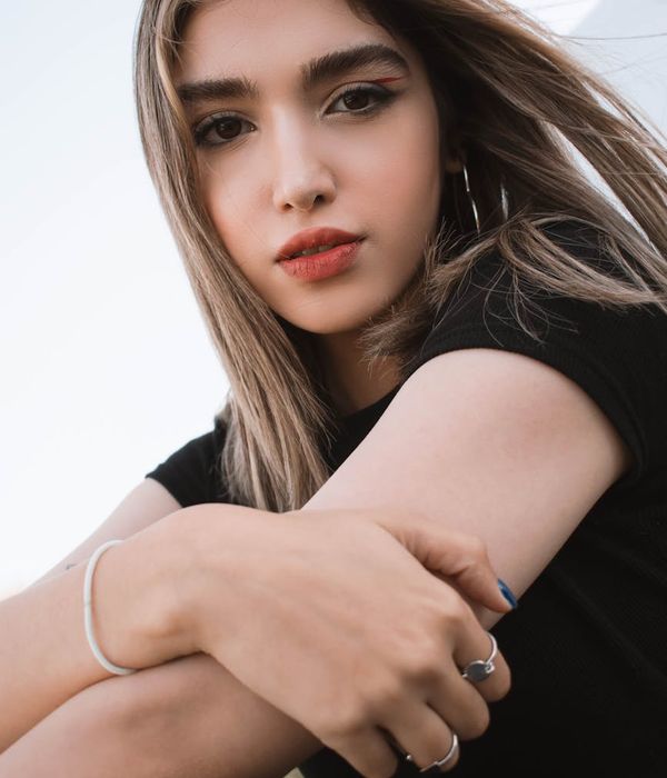 Woman in a calm yoga pose against a dark background with light blue accents.